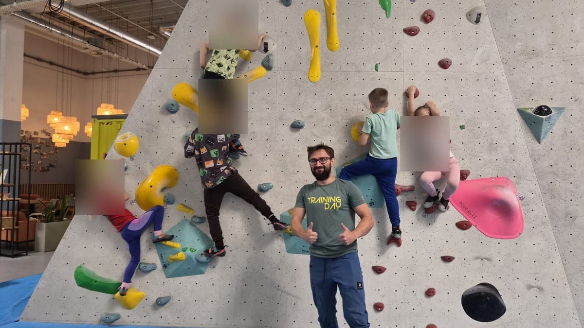 Dzieci wspinają się na ścianie boulderowej podczas zajęć z instruktorem